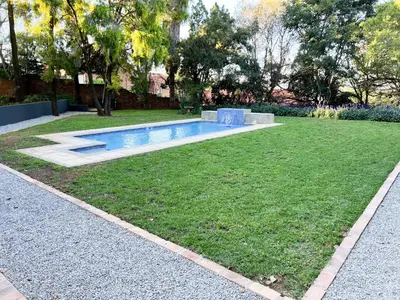 a backyard with a swimming pool in the grass at Afrique134 Olive Tree Private Courtyard Suite in Pretoria