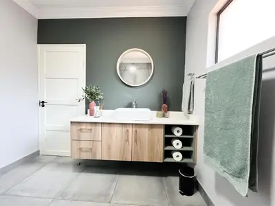 a bathroom with a sink and a mirror at Afrique134 Olive Tree Private Courtyard Suite in Pretoria