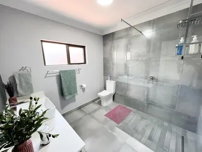 a bathroom with a shower and a toilet and a sink at Afrique134 Olive Tree Private Courtyard Suite in Pretoria