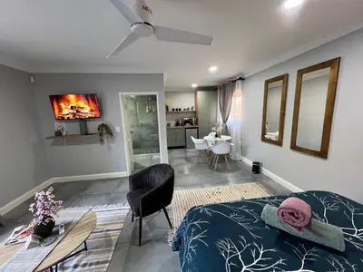 a bedroom with a bed and a dining room at Afrique134 Olive Tree Private Courtyard Suite in Pretoria