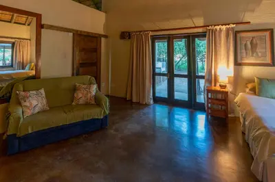 a living room with a couch and a bed and a window at Impisi Accommodation in Phalaborwa