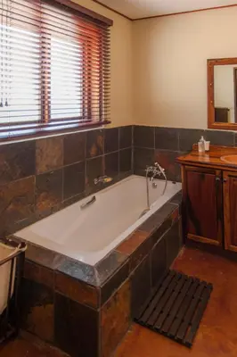 a large bath tub in a bathroom with a window at Impisi Accommodation in Phalaborwa