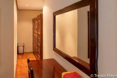a mirror on a wall next to a wooden table at Impisi Accommodation in Phalaborwa
