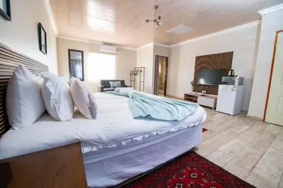 a bedroom with a large white bed and a television at Tintswalo Elegant Apartments in Giyani