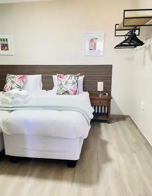 a bedroom with a large white bed with a wooden headboard at Tintswalo Elegant Apartments in Giyani
