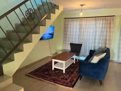 a living room with a table and a staircase at Tintswalo Elegant Apartments in Giyani