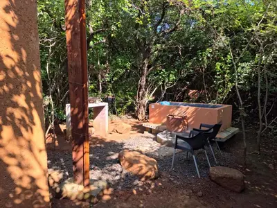 a dog laying next to a table and a chair at Hartbeest Bush Stay #3 in Hartbeespoort