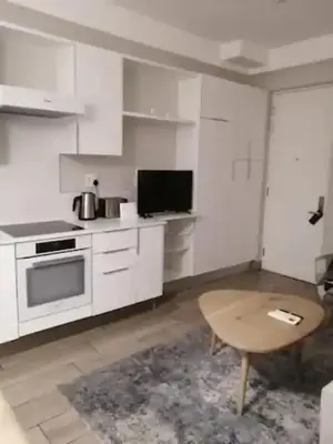 a kitchen with white cabinets and a table and a tv at Premier Lifestyle at The Regency in Pretoria