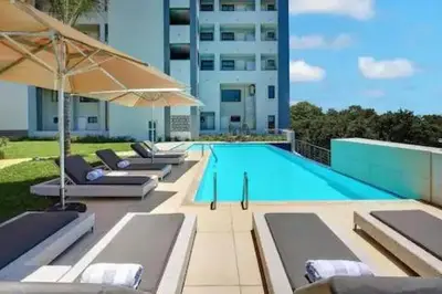 a swimming pool with lounge chairs and an umbrella at Premier Lifestyle at The Regency in Pretoria