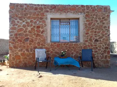 two chairs and a table in front of a stone wall at KGOLA SAFARIS in Rosslyn
