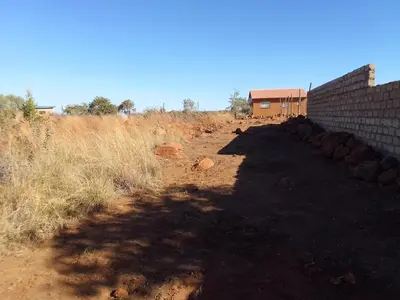 a dirt road in a field next to a building at KGOLA SAFARIS in Rosslyn