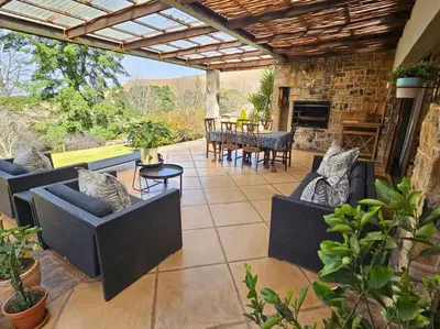 an outdoor patio with couches and a table and chairs at Stone Cottage in Dullstroom