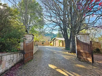 a driveway with two wooden gates on a brick road at Stone Cottage in Dullstroom