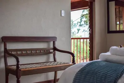 a bedroom with a bed and a window with a porch at DullVino Apartment 8 at Millers Cove in Dullstroom