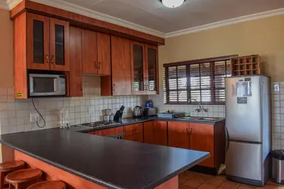 a kitchen with a stainless steel refrigerator and wooden cabinets at DullVino Apartment 8 at Millers Cove in Dullstroom