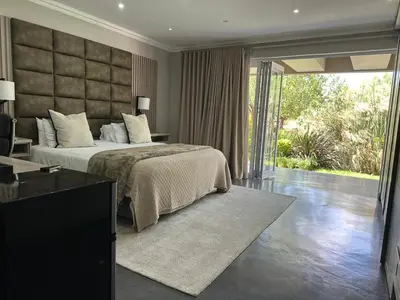 a bedroom with a large bed and a sliding glass door at Decollage Estate in Polokwane