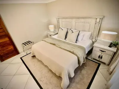 a bedroom with a large bed with white sheets and pillows at Decollage Estate in Polokwane