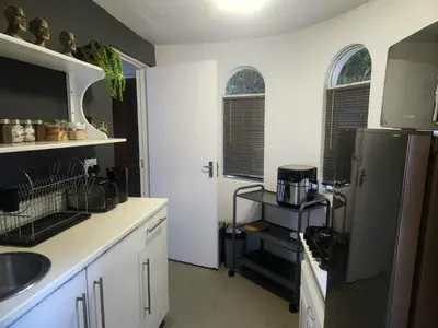 a kitchen with white cabinets and a black refrigerator at The Bardolino Artists Retreat in Nelspruit