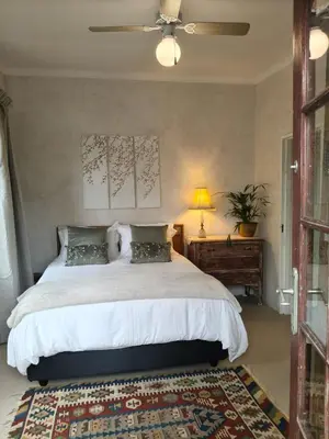 a bedroom with a large bed with a ceiling fan at The Bardolino Artists Retreat in Nelspruit