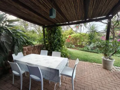 a white table and chairs on a brick patio at The Bardolino Artists Retreat in Nelspruit