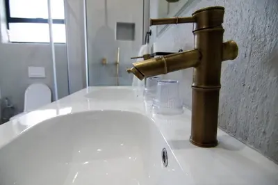 a gold faucet on a white sink in a bathroom at Sihlangu Lodge in Marloth Park