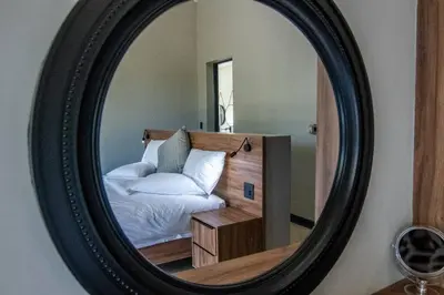 a mirror reflecting a bed in a bedroom at Sihlangu Lodge in Marloth Park