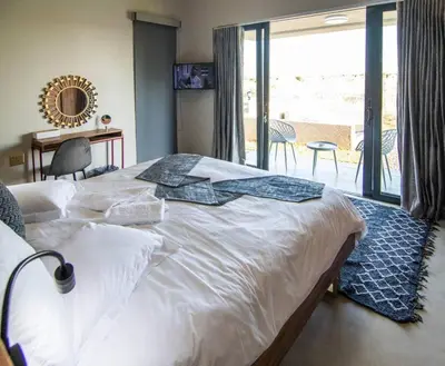 a large white bed in a bedroom with a balcony at Sihlangu Lodge in Marloth Park
