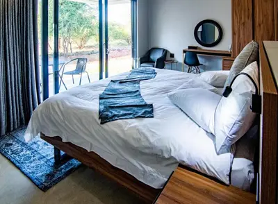 a bedroom with a bed and a large window at Sihlangu Lodge in Marloth Park
