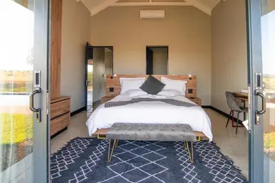 a bedroom with a large bed and a desk at Sihlangu Lodge in Marloth Park