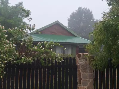 a house with a fence in front of it at Cinnamon & Sage Country Cabins in Dullstroom