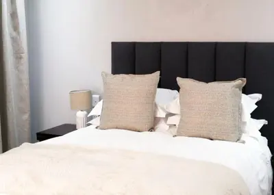 a bedroom with a white bed with a black headboard at Elson Manor Guesthouse in Tzaneen