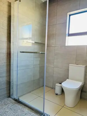 a bathroom with a toilet and a glass shower at Elson Manor Guesthouse in Tzaneen