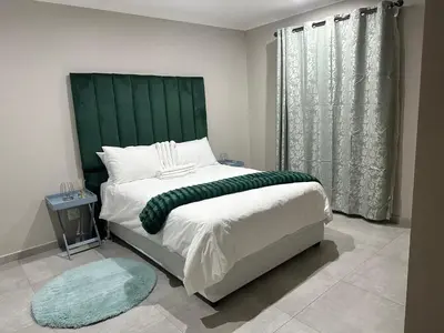 a bedroom with a large bed with a green headboard at Nyeza homes in Secunda