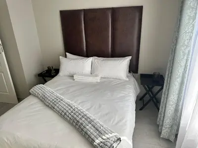a white bed with a brown headboard and white pillows at Nyeza homes in Secunda