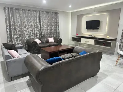 a living room with two couches and a flat screen tv at Nyeza homes in Secunda