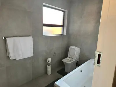 a bathroom with a white toilet and a window at Nyeza homes in Secunda