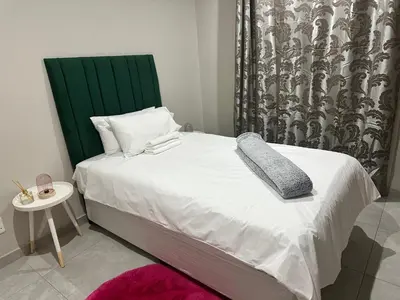 a bedroom with a bed with a green headboard and a table at Nyeza homes in Secunda