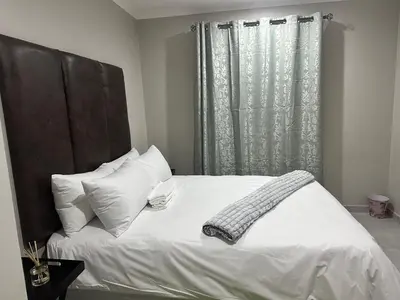 a bed with white sheets and pillows and a window at Nyeza homes in Secunda