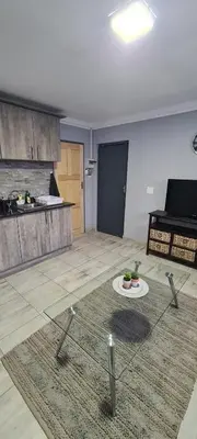 a living room with a kitchen and a table at Cozy Little Nest in Pretoria