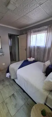 a bedroom with a large white bed and a window at Cozy Little Nest in Pretoria