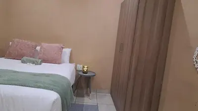 a bedroom with a bed next to a wooden door at Cozy Airport Stay in Kempton Park