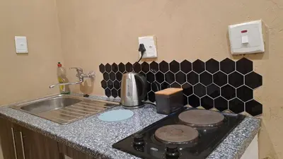 a kitchen counter with a stove and a sink at Cozy Airport Stay in Kempton Park