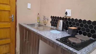 a kitchen counter with a sink and a stove at Cozy Airport Stay in Kempton Park