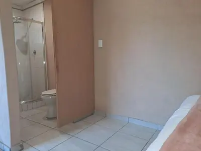 a bathroom with a shower and a toilet in it at Cozy Airport Stay in Kempton Park