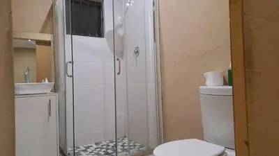 a bathroom with a shower and a toilet and a sink at Cozy Airport Stay in Kempton Park