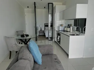 a living room with a couch and a table in a kitchen at Xquisite Ellipse Apartment in Midrand