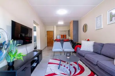 a living room with a couch and a tv at The Waterfallcity Charm next to Mall of Africa in Midrand