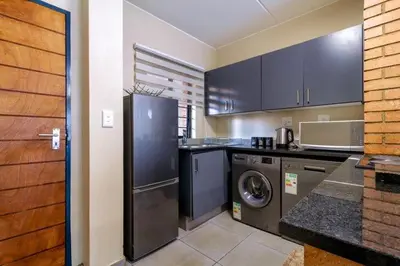 a kitchen with a refrigerator and a washer and dryer at The Waterfallcity Charm next to Mall of Africa in Midrand