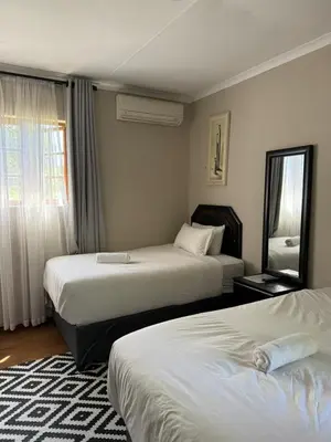 a hotel room with two beds and a window at The Eden Boulders Hotel and Resort Midrand in Midrand