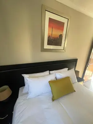 a bed with white pillows and a picture on the wall at The Eden Boulders Hotel and Resort Midrand in Midrand
